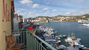 A balcony with a view of a harbor, boats, and a town in the background.
