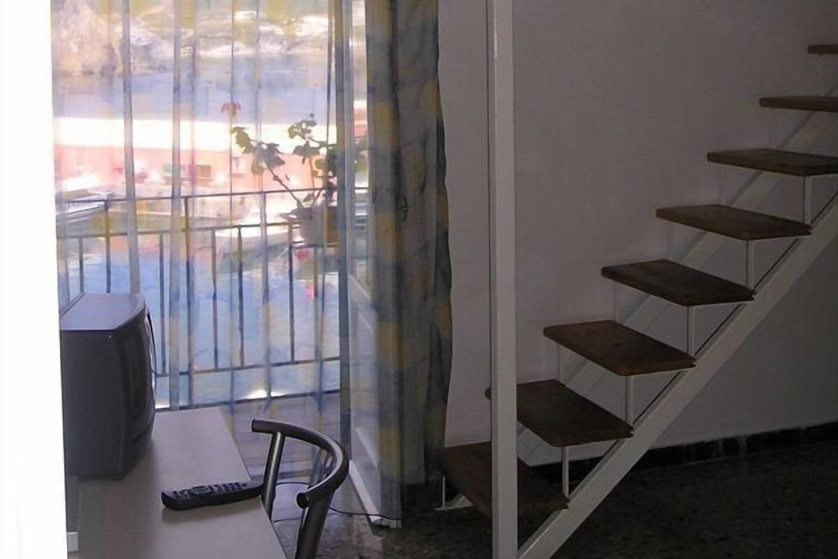 Una habitación con literas, un escritorio con silla, una televisión y una ventana con vistas al paisaje.