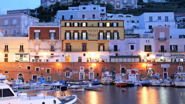A waterfront hotel with multiple balconies, a marina with boats, and buildings with signage.