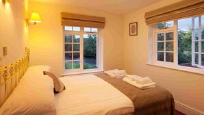 A hotel room with a bed, two windows with blinds, a wall-mounted lamp, and a ceiling light. - Anchor Inn (Dulverton)
