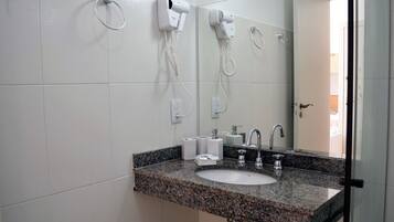 A bathroom with a granite countertop sink, a mirror, a hairdryer, and a towel ring.