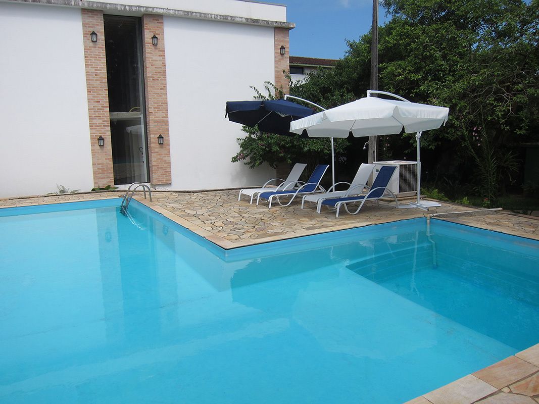 Una piscina al aire libre, sombrillas, sillones reclinables de piscina