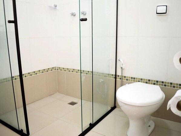 Une salle de bain avec une douche à parois de verre, des toilettes et un lavabo.
