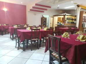 A restaurant with tables covered in red tablecloths and chairs with yellow napkins.
