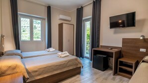 Een hotelkamer met twee bedden, een bureau, een televisie en een airconditioning.
