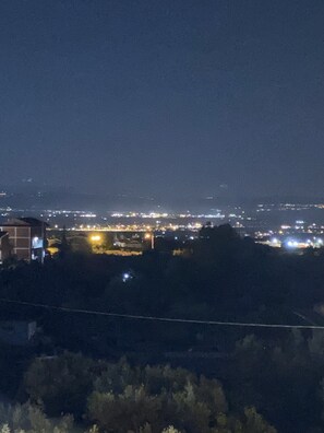 A nighttime cityscape with illuminated buildings and a distant view of a city skyline.
