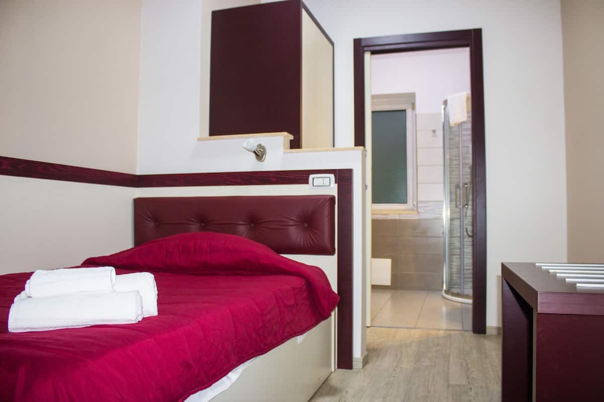 A hotel room with a bed, a bathroom with a shower, and a desk.