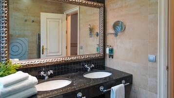 Un baño con dos lavamanos, un espejo grande y un perchero para toallas.