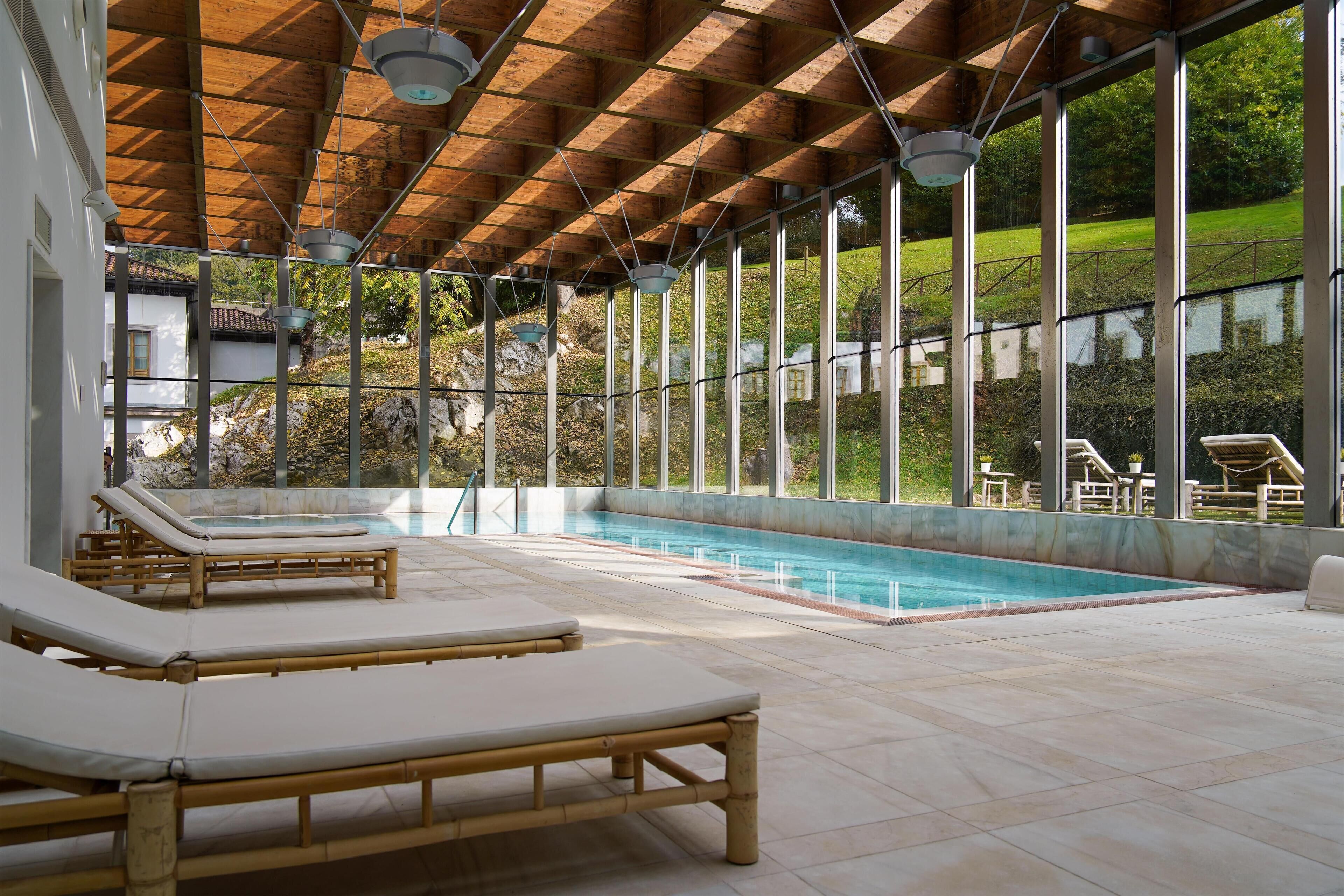 Zona de piscina con tumbonas de madera y vistas a un paisaje natural.