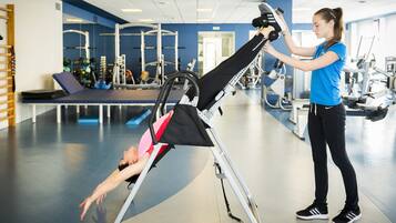 Ett gym med träningsutrustning och en person som ligger på en matta.