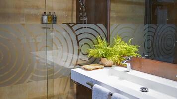 Een moderne badkamer met een douchecabine van glas, een witte wastafel en een spiegel met een rond ontwerp.