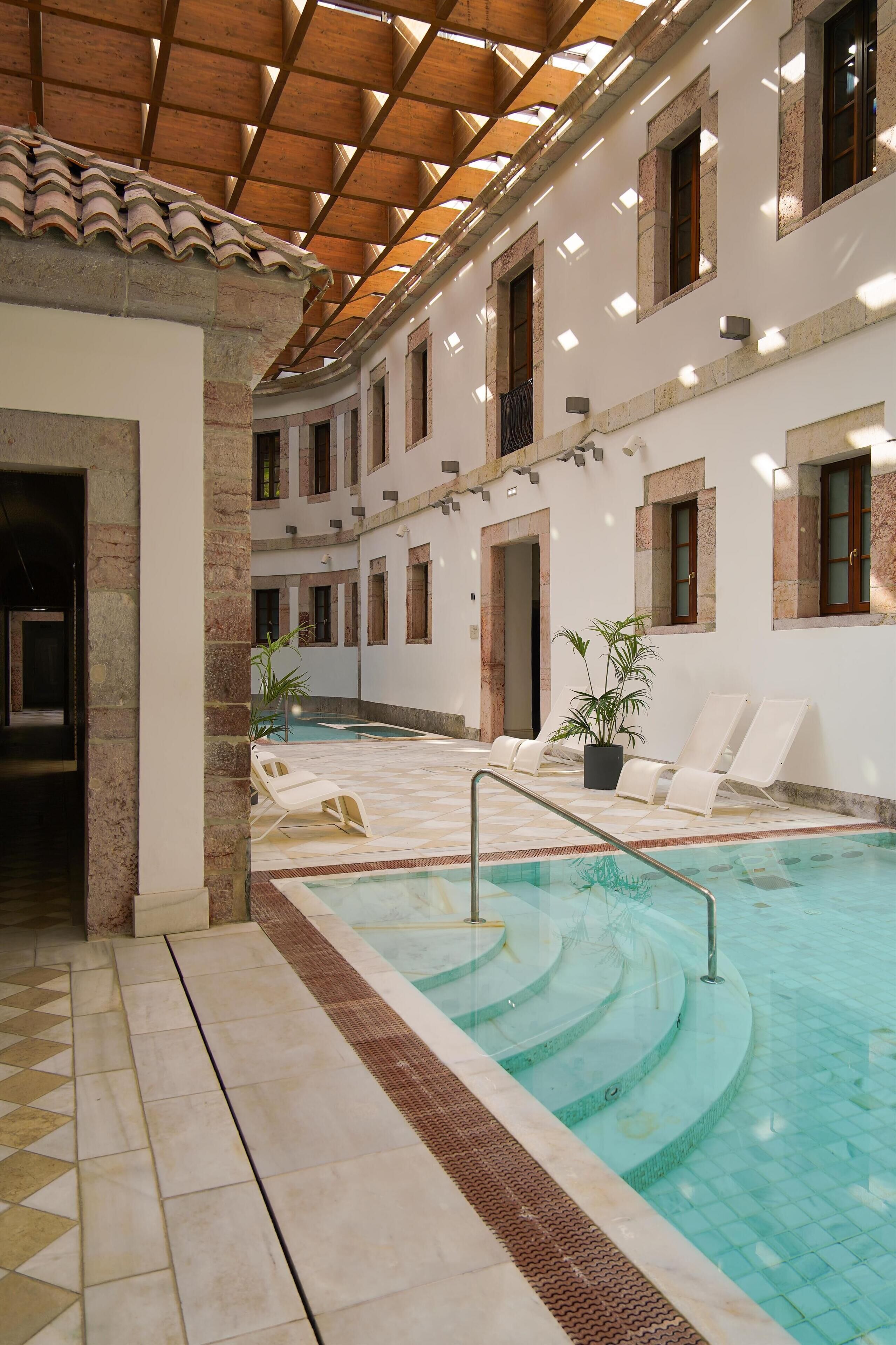 An indoor swimming pool with tiled flooring and a wooden ceiling.