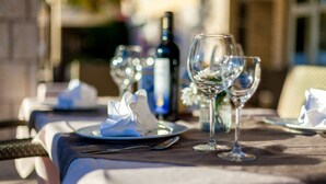 Een eettafel gedekt met borden, wijnglazen en een fles wijn, wat doet denken aan een restaurant.