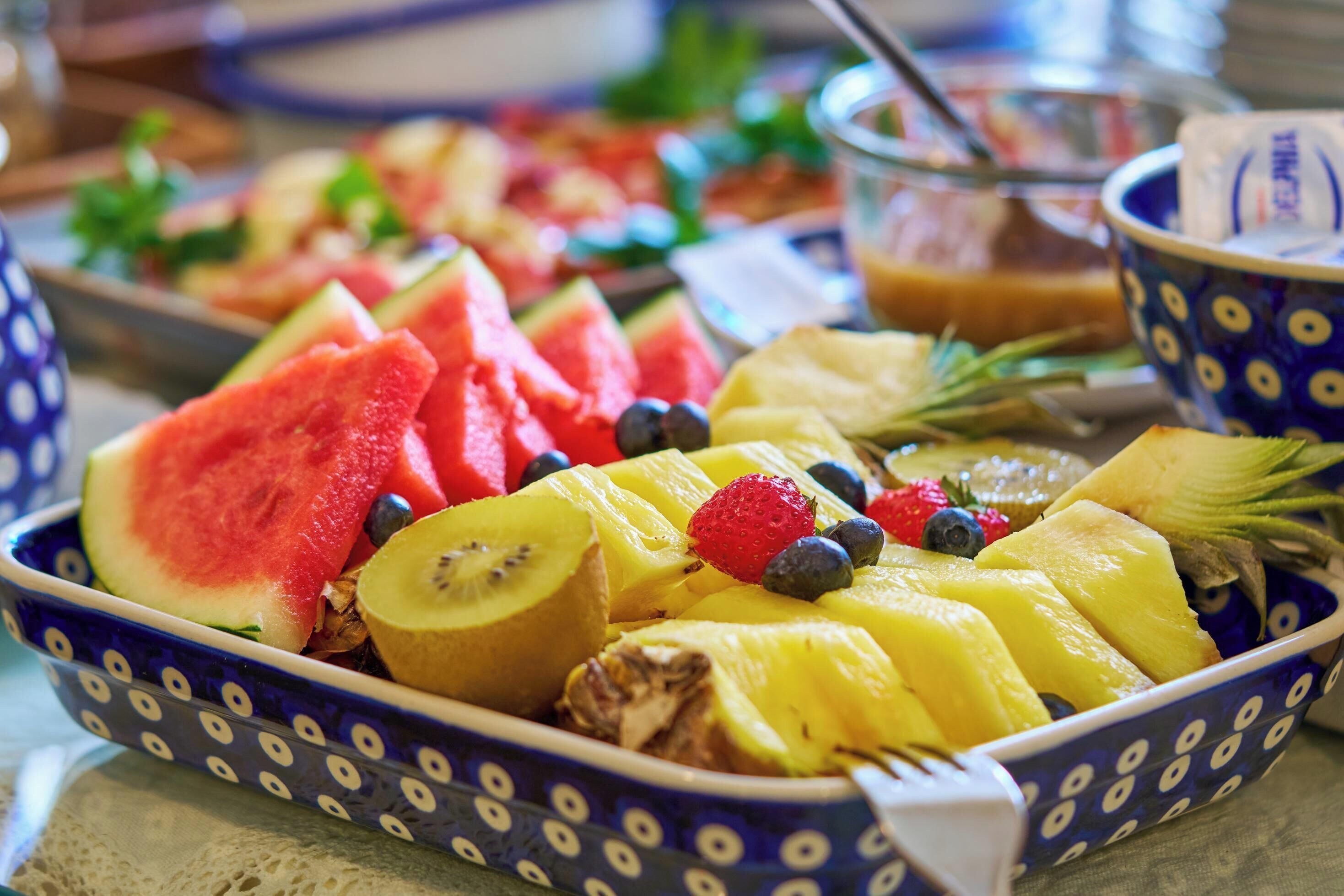 En fruktskål med vattenmelon, kiwi, ananas, jordgubbar och blåbär.