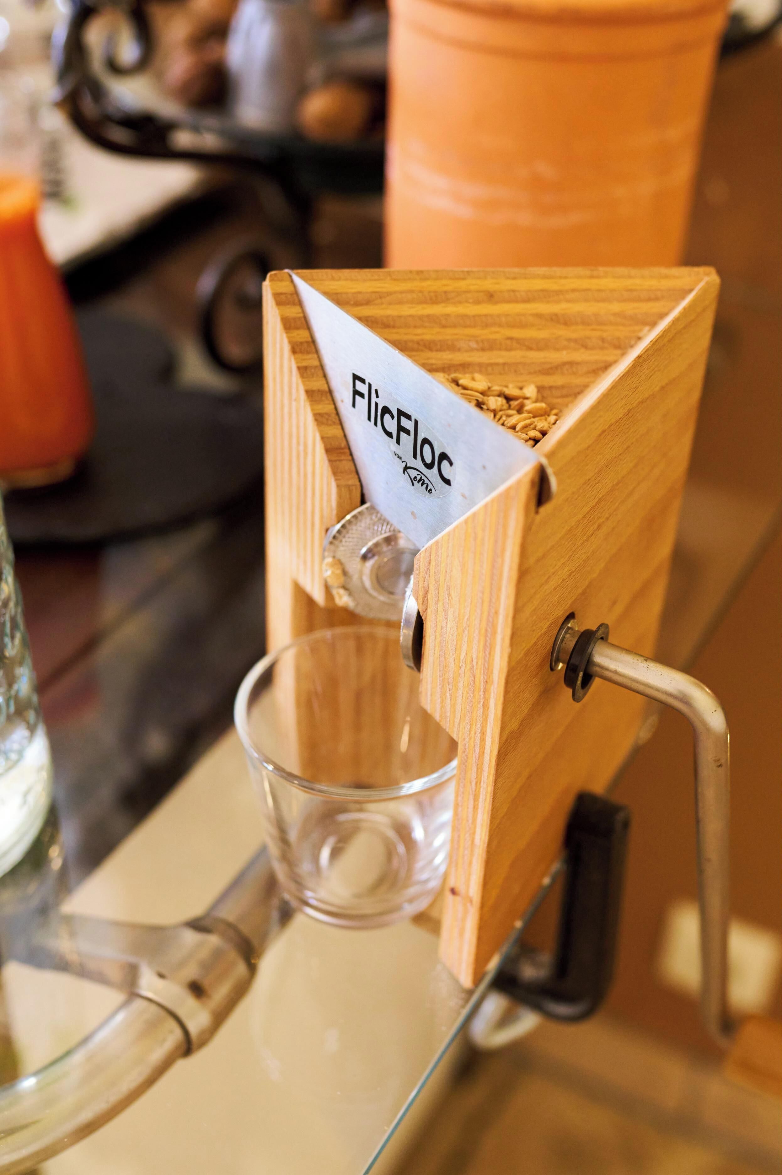 Eine Holz-Kaffeemühle mit dem Aufdruck 'FlicFloc' und einem darunterliegenden Glasbehälter.