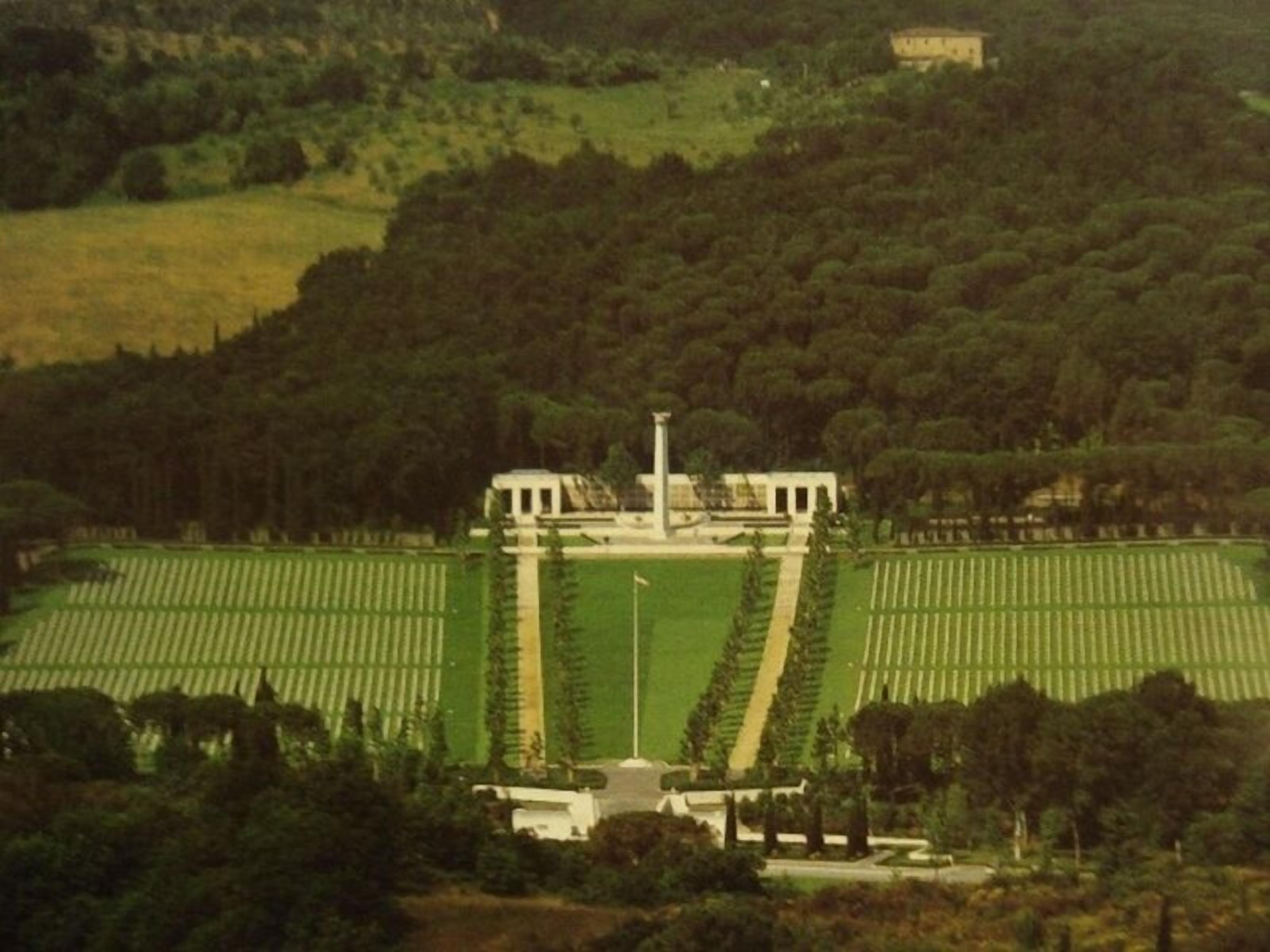 A large, open field with a central building surrounded by trees.