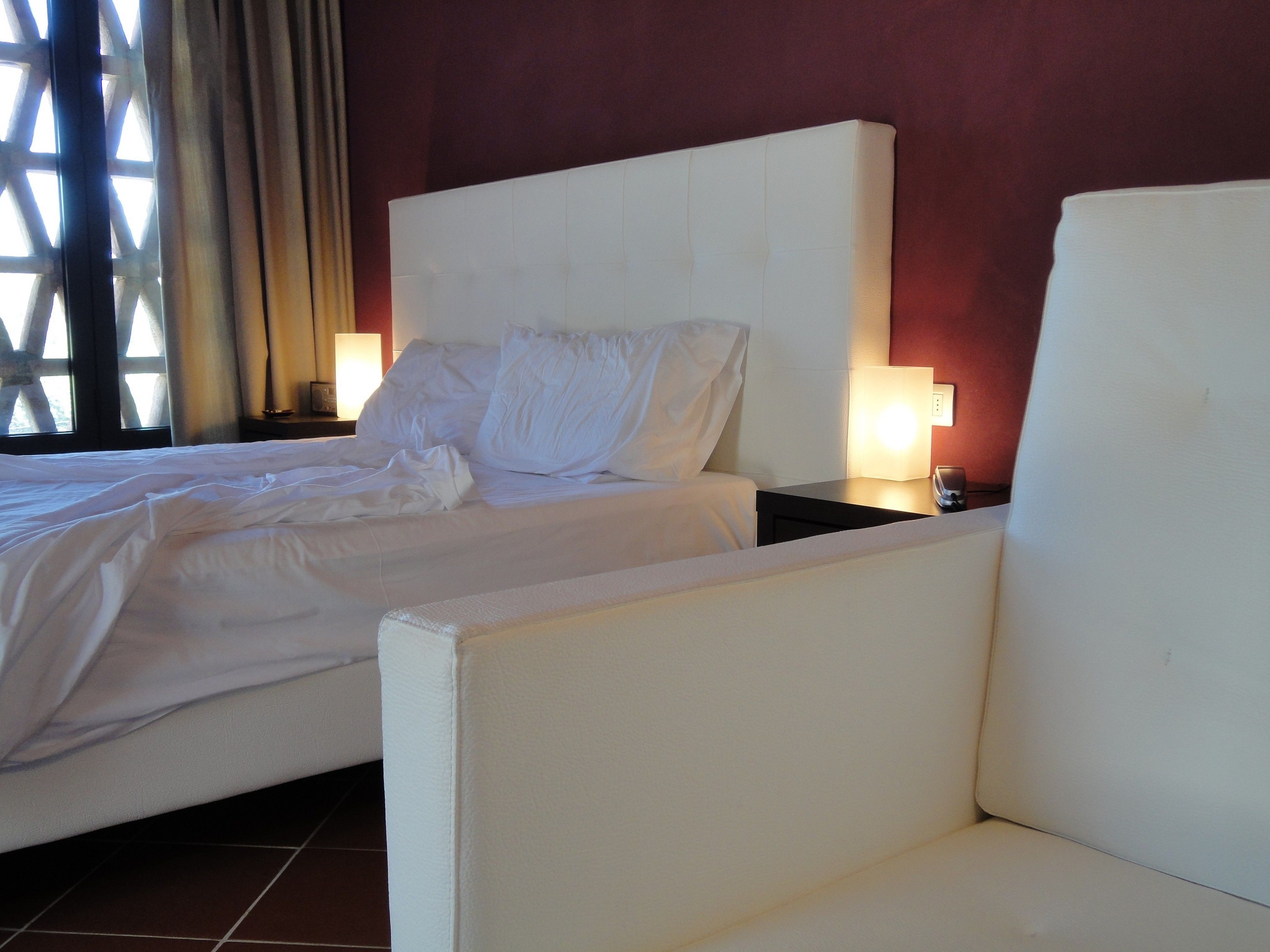 Una habitación de hotel con una cama grande, dos mesitas de noche y una silla.