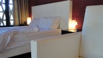 Une chambre d’hôtel avec un grand lit, deux tables de chevet et une chaise.