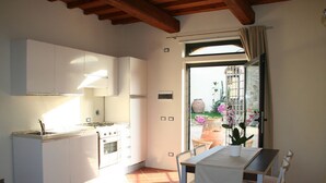 Una cocina con armarios blancos, una estufa y un comedor con una mesa y sillas.