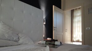 Una habitación de hotel con una cama grande, una mesita de noche y una puerta que da a otra habitación.