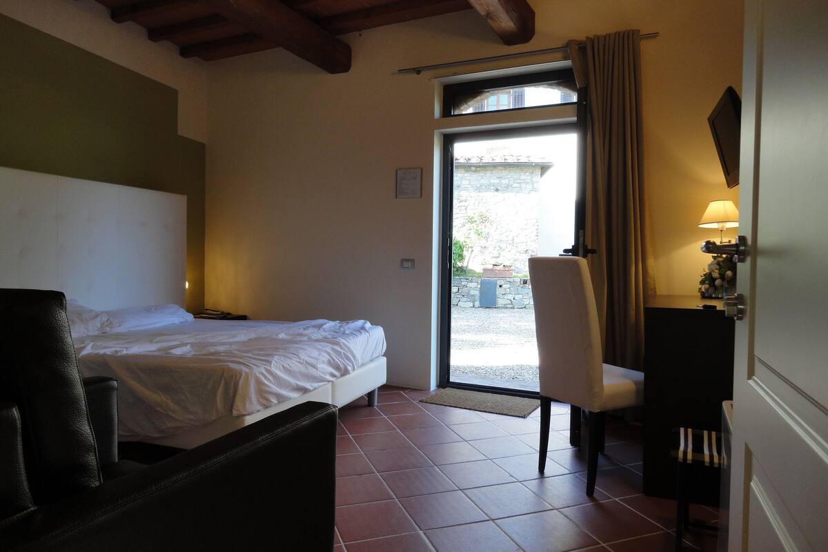 Una habitación de hotel con cama, una silla, un escritorio y una ventana con cortinas.