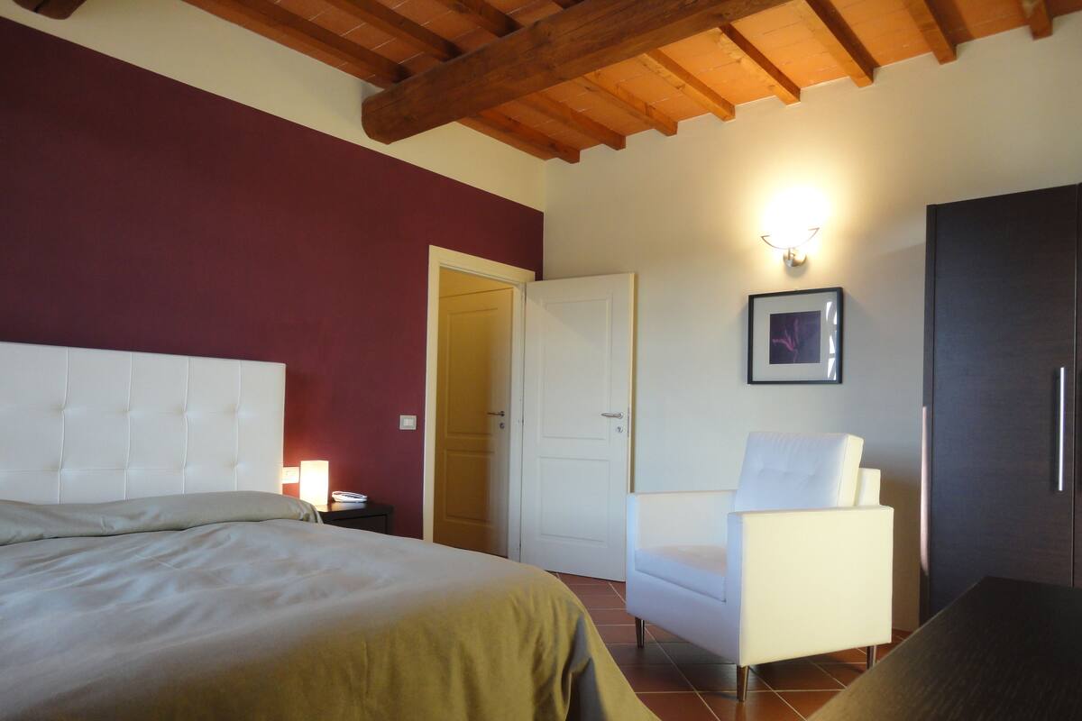 Un dormitorio con cama, una silla, un armario y una puerta.