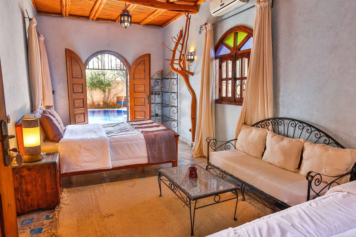 A bedroom with a bed, a sofa, a table, and a decorative tree branch.