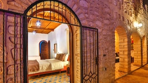 A room with a checkered floor, a bed with pillows, a wooden ceiling, and stone walls. - Riad Dar Etto (Essaouira)