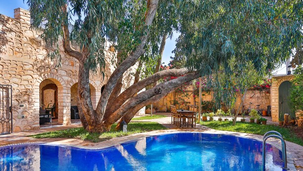 A swimming pool with a stone building in the background. - Riad Dar Etto (Essaouira)