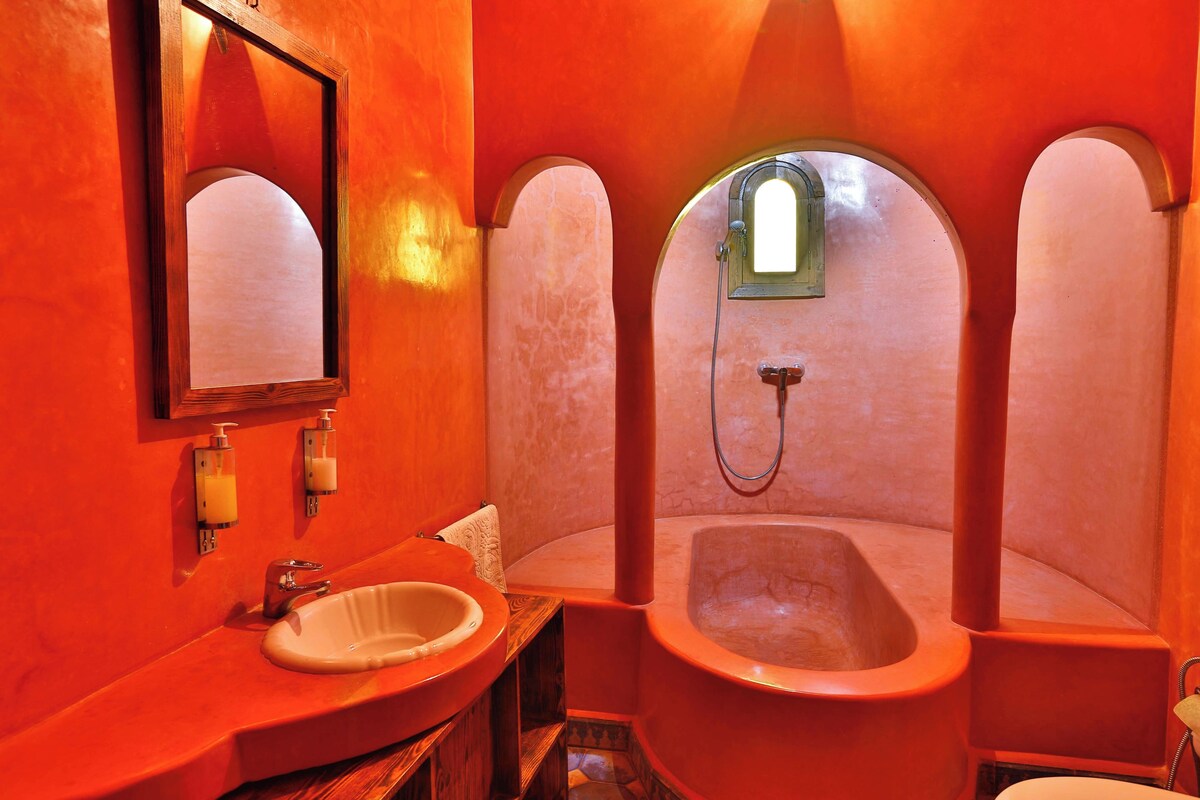 Un baño con un lavamanos de madera, un espejo y dos cabinas de baño con arco.