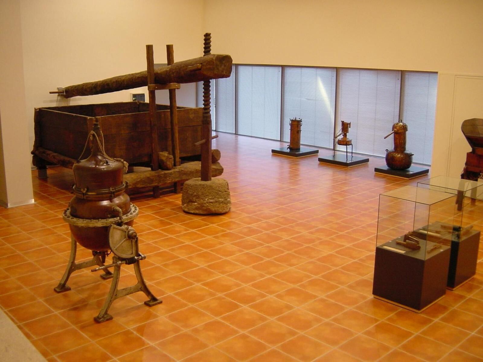 Exposição interna com maquinaria histórica, incluindo uma grande estrutura de madeira e dispositivos metálicos em exibição.