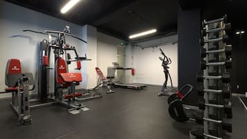 Un gimnasio con diferentes equipos de ejercicio, incluyendo una cinta de correr, máquinas de pesas y una estructura para sentadillas.