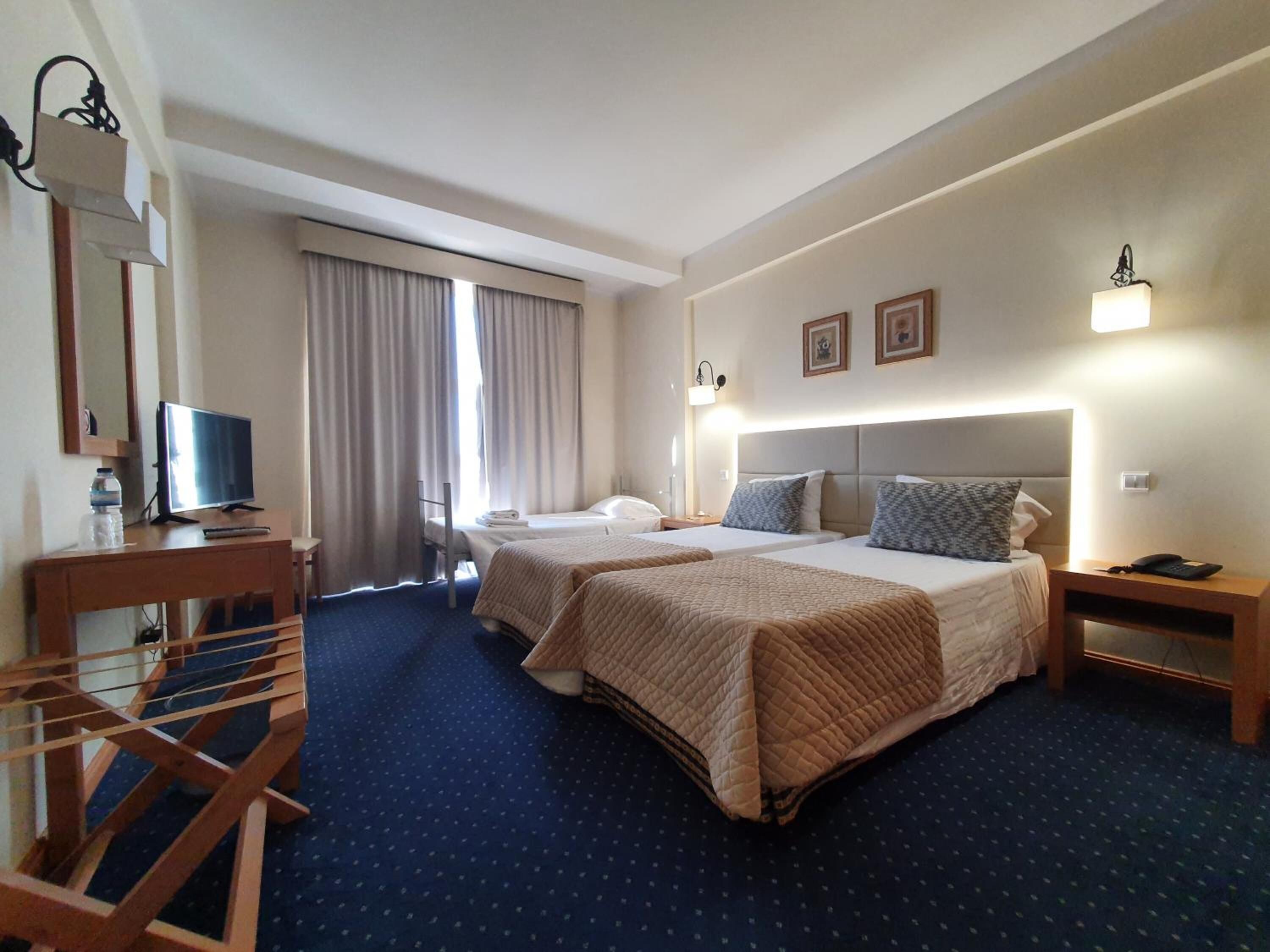 A hotel room with two beds, a desk with a computer, a TV, and a staircase.