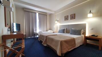 A hotel room with two beds, a desk with a computer, a TV, and a staircase.