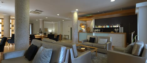 A modern living area with sofas, a coffee table, and a bar area with bottles.