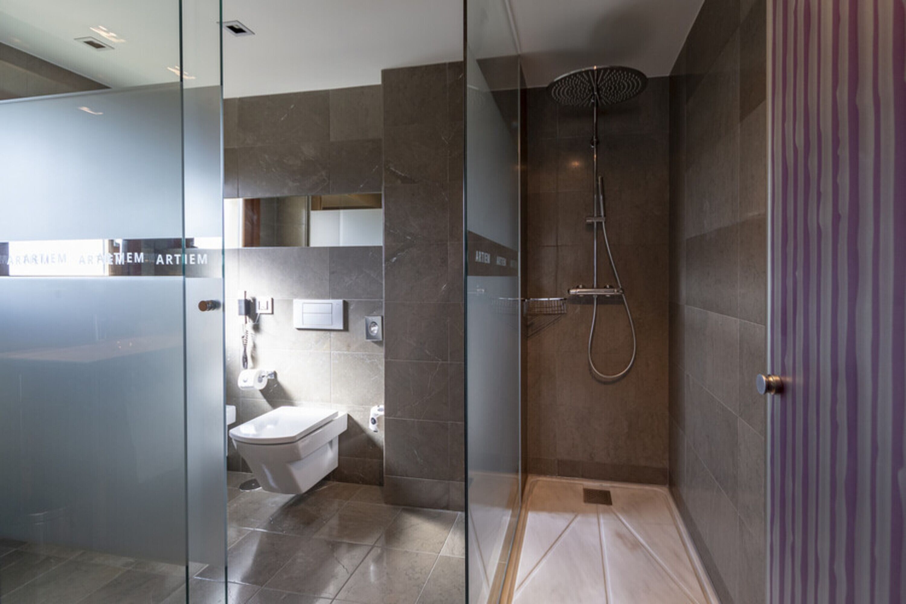 Un baño moderno con cabina de ducha de vidrio, inodoro y lavamanos.