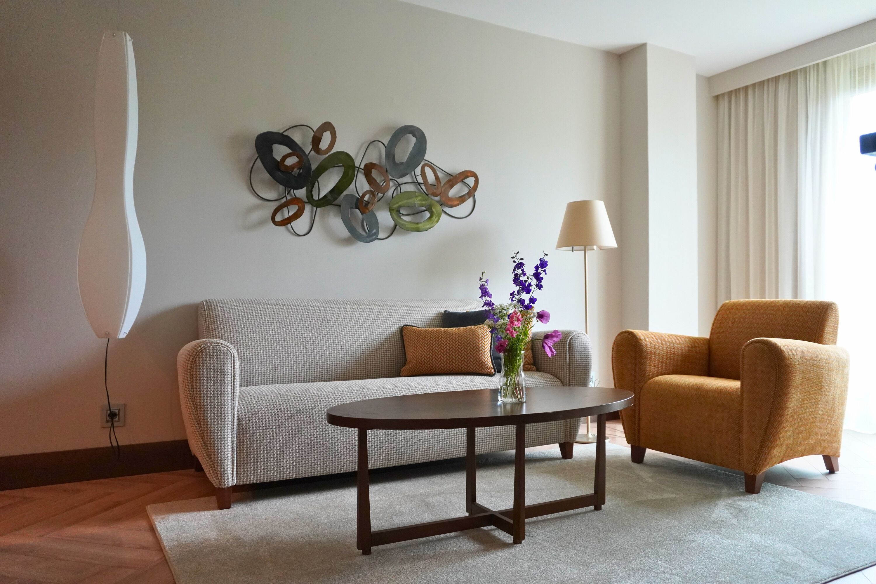 Una sala de estar con sofá, sillón, mesa de centro y decoración en la pared.