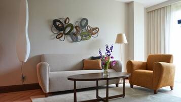 Una sala de estar con sofá, sillón, mesa de centro y decoración en la pared.