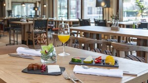 A restaurant setting with wooden tables, chairs, and a glass of orange juice on a table. - ARTIEM Asturias (Villaviciosa)