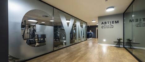 A gym with mirrored walls, wooden flooring, and exercise equipment.