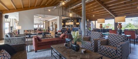 A spacious living area with a high ceiling, exposed beams, and modern lighting fixtures.