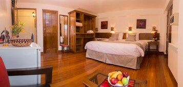 Habitación de hotel con una cama grande, armario de madera y zona de comedor con mesa y sillas.