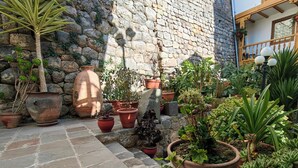 A courtyard with stone walls, various potted plants, and a tiled floor. - Hotel Rumi Punku (Cusco)