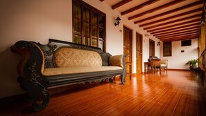 A traditional room with a wooden floor, a sofa with ornate carvings, a wooden table, and a chair. - Hotel Rumi Punku (Cusco)