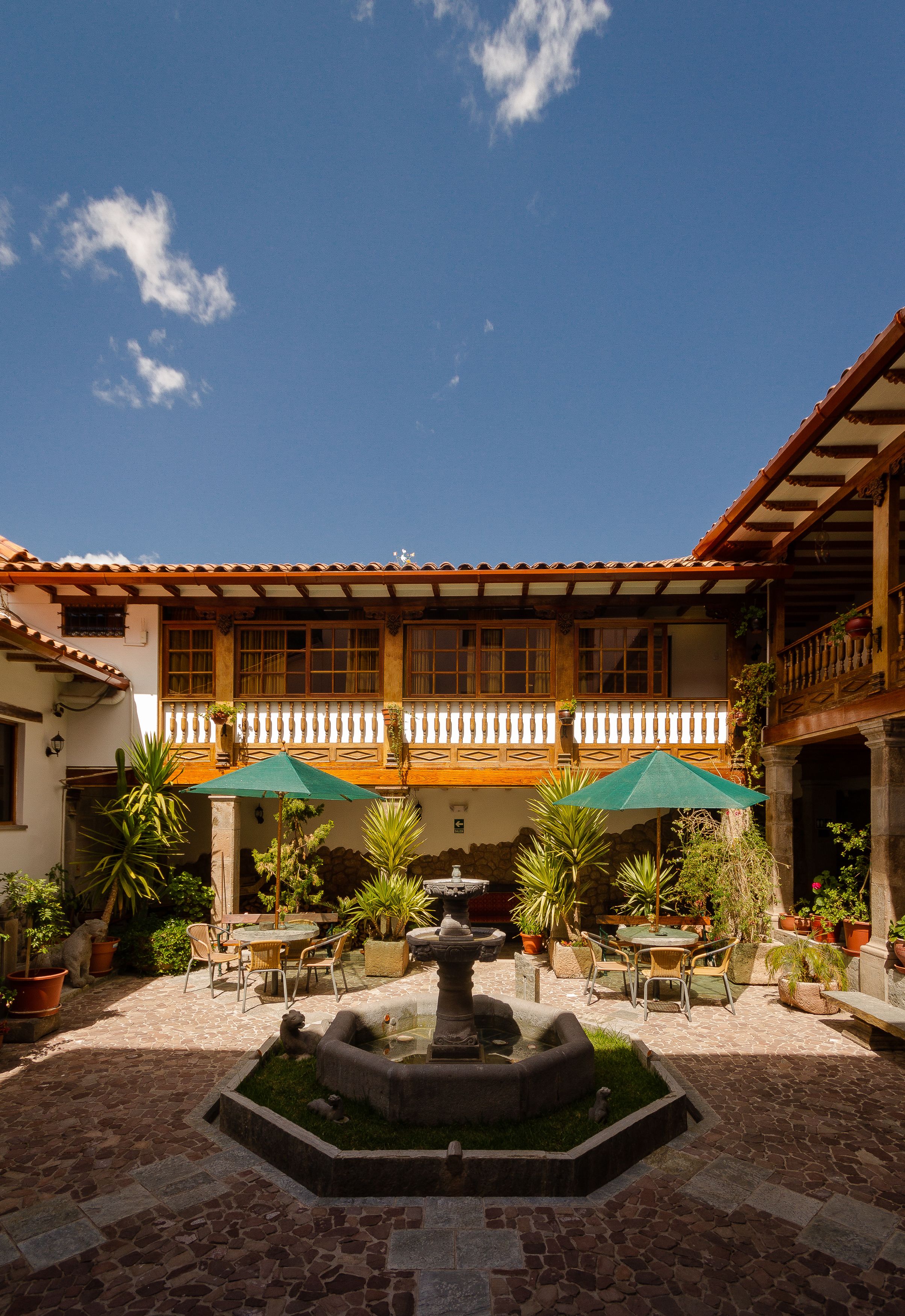 A courtyard with a fountain, outdoor seating, and potted plants.