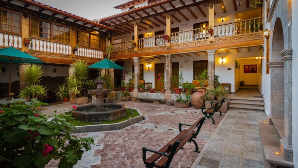 A courtyard with stone flooring, potted plants, a fountain, and benches. - Hotel Rumi Punku (Cusco)