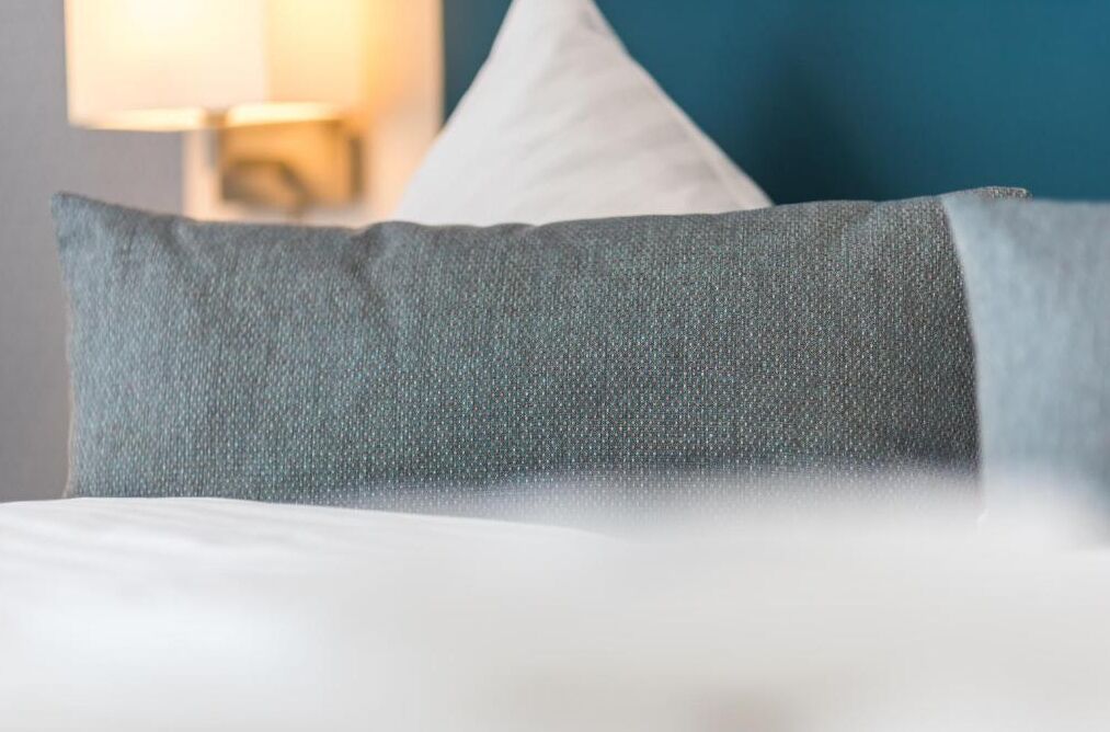 A bed with a grey pillow and a white pillow.