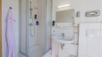 A modern bathroom with a glass-enclosed shower, a white sink, and a mirror above the sink.
