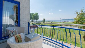 Ein Balkon mit Korbmöbeln und Blick auf das Meer.