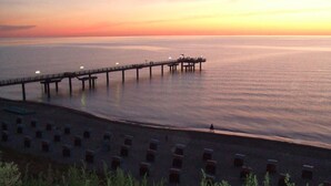 Eine Pier, die sich in ruhiges Wasser bei Sonnenuntergang erstreckt.